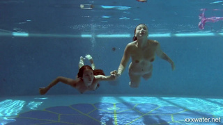 Две молодые девушки плавают голышом в крытом бассейне